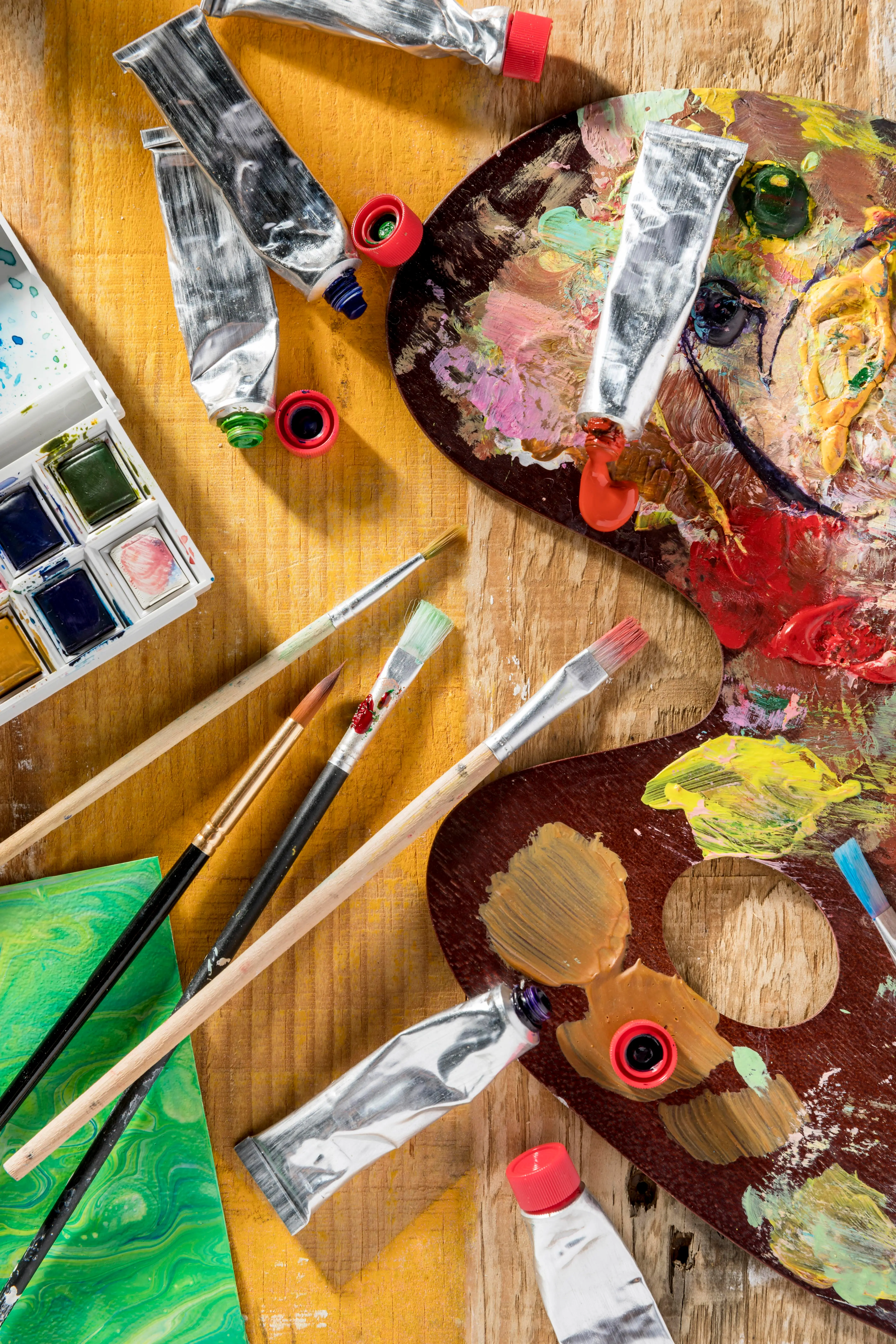 Mesa con materiales de arte, como pinceles, pinturas y papeles de colores.